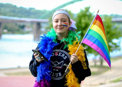A young girl holds a LGBTQ flag
