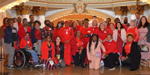 Educators in red pose inside the Mississippi state capitol building.