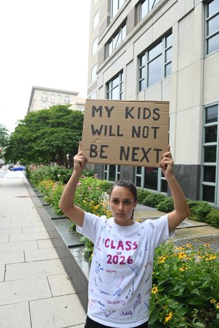 a woman hold up a sign that says "my kids will not be next"