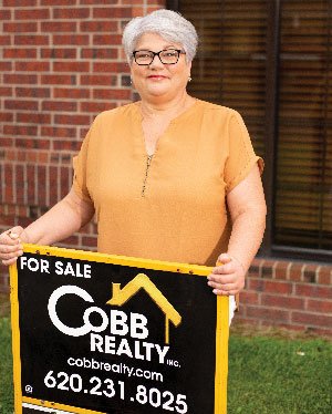 Kansas retiree Mary Geier at a real estate for sale sign.