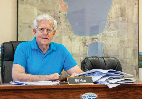 Orleans, IA Mayor Bill Maas at his desk in front of a wall map.