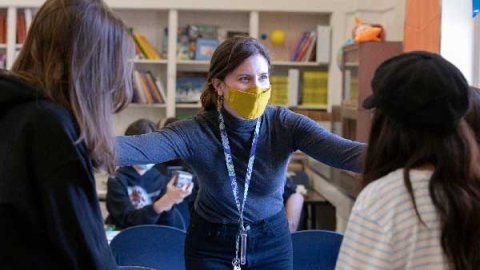 SFUTR graduate Cecilia Frisardi, wearing a mask, has her hands on her students' shoulders