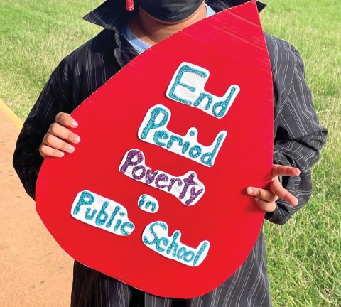 Student holding sign that says, End Period Poverty in Public Schools