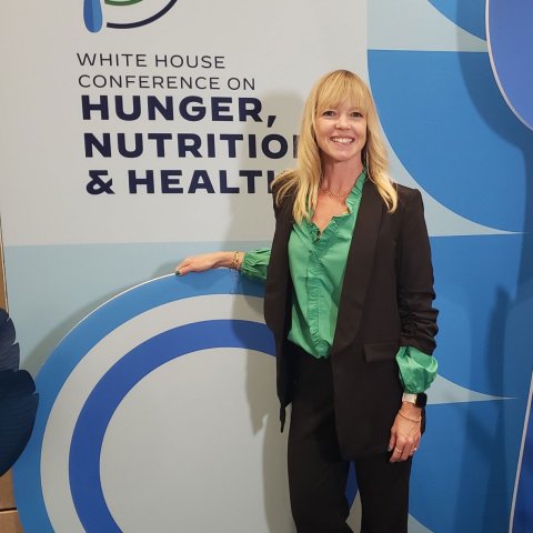 Cathy Grano stands in front of a sign for the White House Conference on Nutrition, Hunger and Health