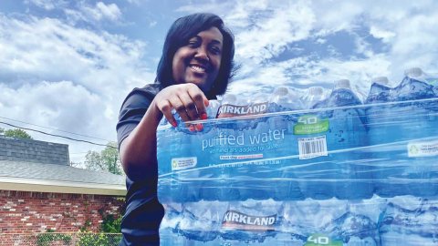 In Jackson, Miss., association president Erica Jones posing behind a pallet of water bottles..