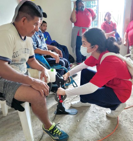 Ariana Campos helping a male amputee with fitting a prosthetic that she learned to build.