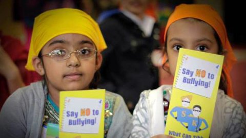 Two young sikh students hold anti-bullying flyers