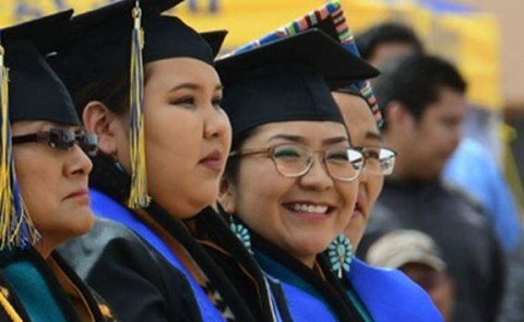 female native american students at their high school graduation wearing native regalia