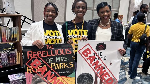 Becky Pringle poses with two educators and hold protest signs at a banned books rally