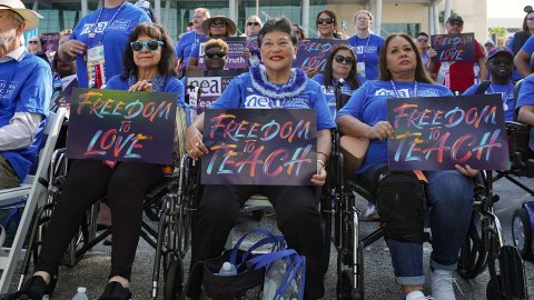 Three women seated in wheelchairs and holding signs attend the Freedom to Learn Rally in Orlando, Florida