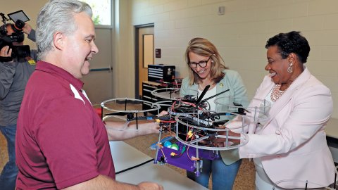NEA President Becky Pringle looks at a large drone with teacher Mike Evele and U.S. Representative Hillary Scholten
