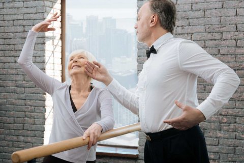 Caucasian male and female Seniors dancing in a studio holding a barre