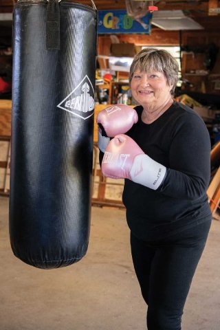 Donna Nielsen posing with boxing gloves in front of a heavy bag.
