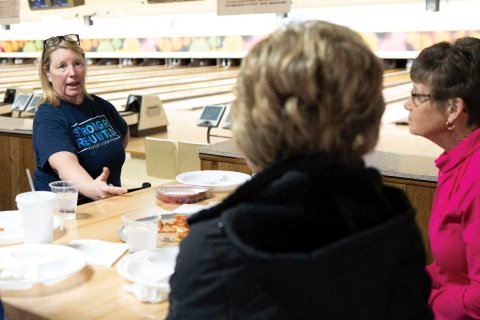 Illinois’ Kari Vanderjack in a discussion with other retirees at a bowling alley table.
